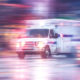 Photo of ambulance racing through city streets on a rainy night