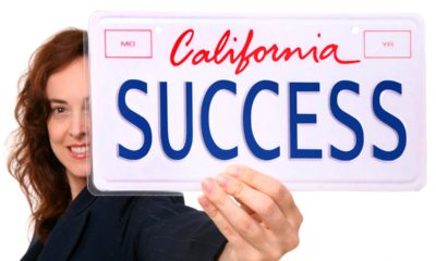 Photo of a woman holding a California license plate that says "Success"